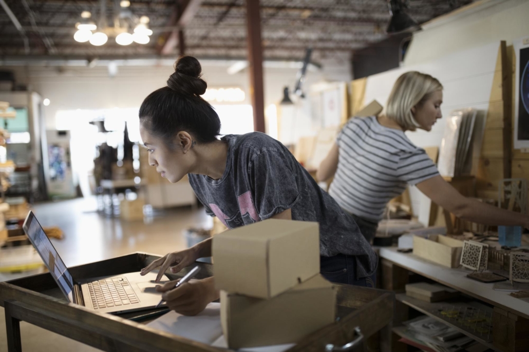 Deux femmes travaillant au milieu des cartons et d'autres objets, travaillants pour le site de e-commerce et gérant leurs envois de colis